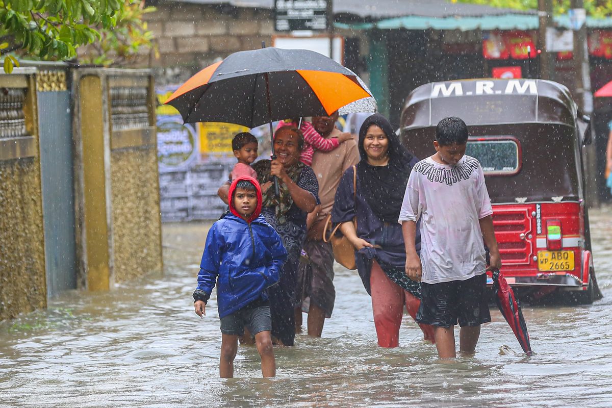 Several residents walk through floodwaters carrying their belongings after heavy rains from Cyclone ''Ditwah'' sweep through Colombo, Sri Lanka, on November 28, 2025. (Photo by Krishan Kariyawasam/NurPhoto) (Photo by Krishan Kariyawasam / NurPhoto via AFP)