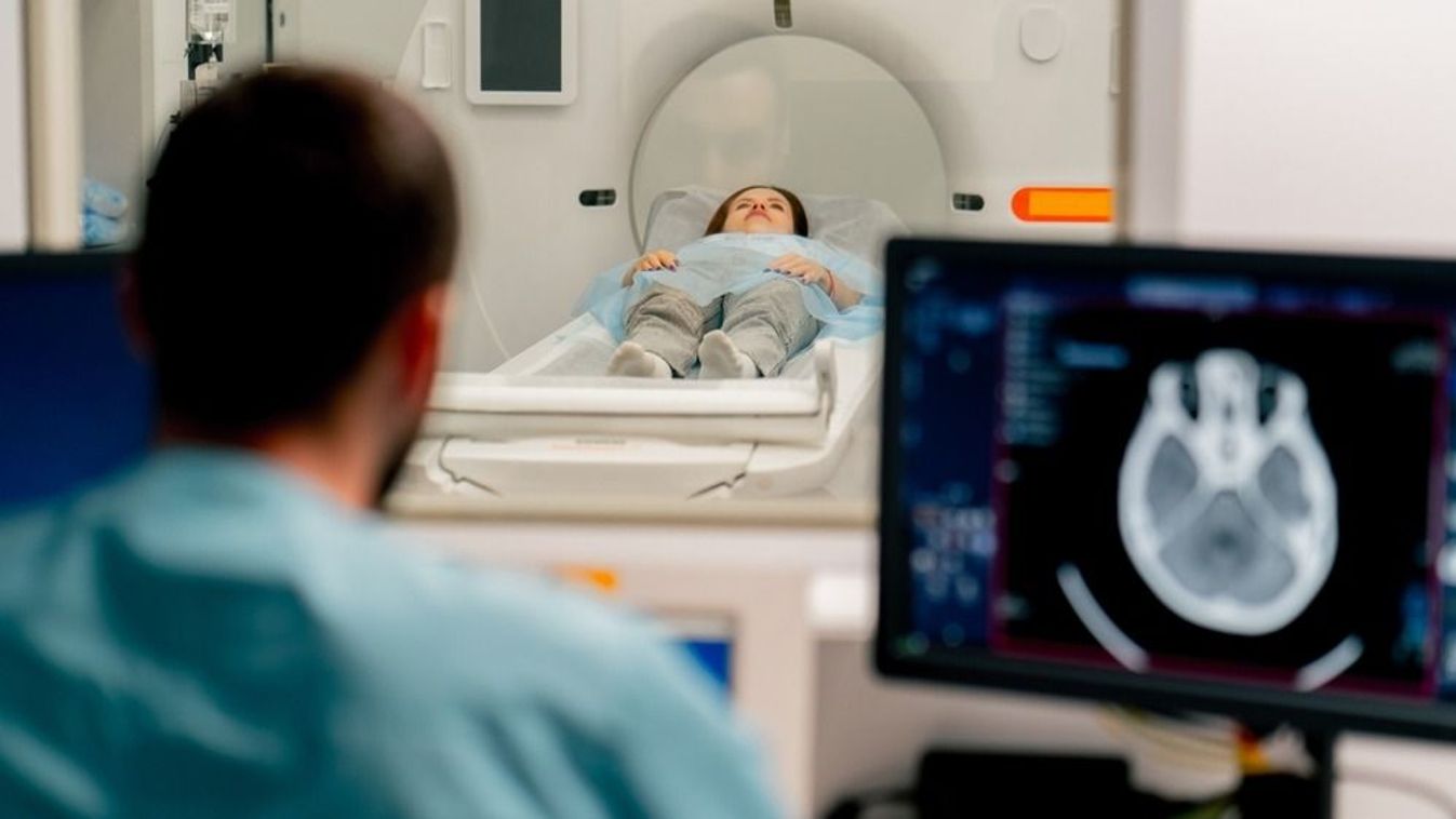 A girl lies on an MRI machine before examining her body and the radiologist gives command to her to prepare for a diagnosis

2386190239