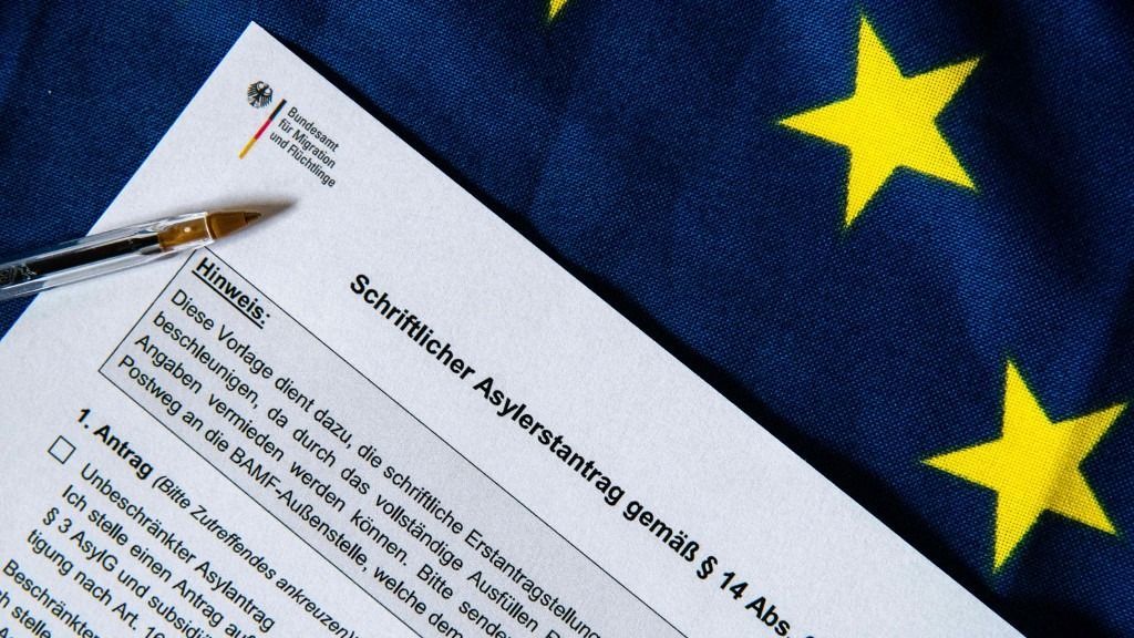ILLUSTRATION - 30 July 2025, Belgium, Brüssel: A form for a written asylum application in accordance with Section 14 (2) of the Asylum Act (AsylG) is on an EU flag. According to the Federal Office for Migration and Refugees (BAMF), the form is intended to facilitate the initial written application in Germany, as filling it out completely can avoid queries due to missing information. Photo: Alicia Windzio/dpa (Photo by Alicia Windzio / dpa Picture-Alliance via AFP)