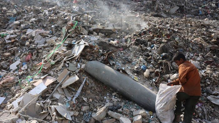 Palesztina - Műanyag szemetet gyűjtő fiú egy fel nem robbant rakéta közelében Gáza városában