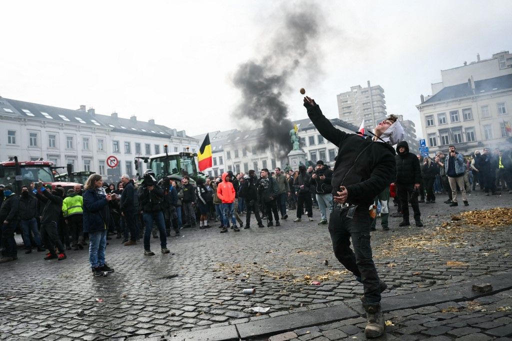 A farmer throws a potato near the European Parliament, during a farmers' protest to denounce the reforms of the Common Agricultural Policy (CAP) and trade agreements such as the Mercosur, in Brussels, on December 18, 2025, organised by Copa-Cogeca, the main association representing farmers and agricultural cooperatives in the EU. EU Farmers, particularly in France, worry the Mercosur deal -- which will be discussed at the EU leaders meeting -- will see them undercut by a flow of cheaper goods from agricultural giant Brazil and its neighbours. They also oppose plans put forward by the European Commission to overhaul the 27-nation bloc's huge farming subsidies, fearing less money will flow their way. (Photo by NICOLAS TUCAT / AFP)