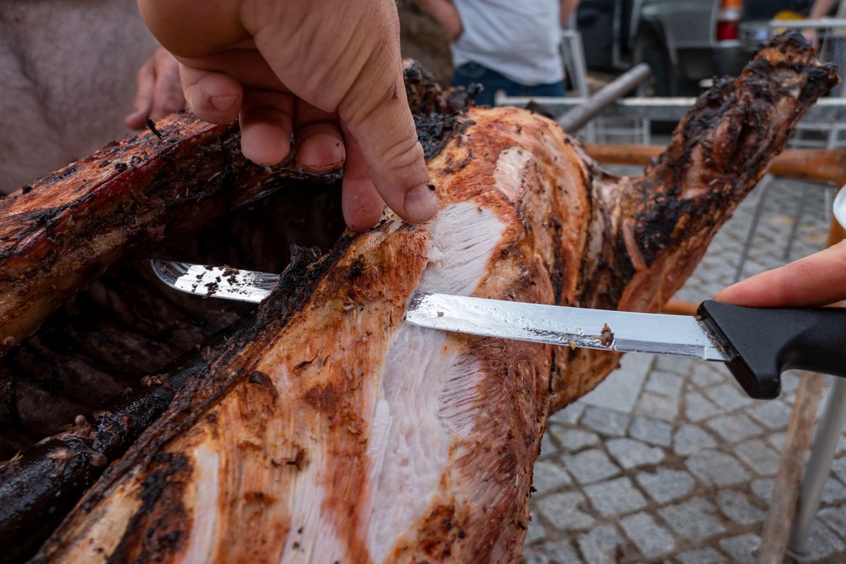 Chef slicing pork on a spit at an outdoor event