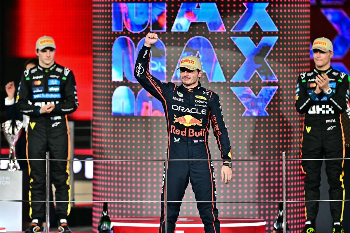 World champion and race third-placed McLaren's British driver Lando Norris (R), watches race winner Red Bull Racing's Dutch driver Max Verstappen (C) celebrating next to second-placed McLaren's Australian driver Oscar Piastri on the podium at the end of the Abu Dhabi Formula One Grand Prix at the Yas Marina Circuit in Abu Dhabi on December 7, 2025. (Photo by Giuseppe CACACE / AFP)