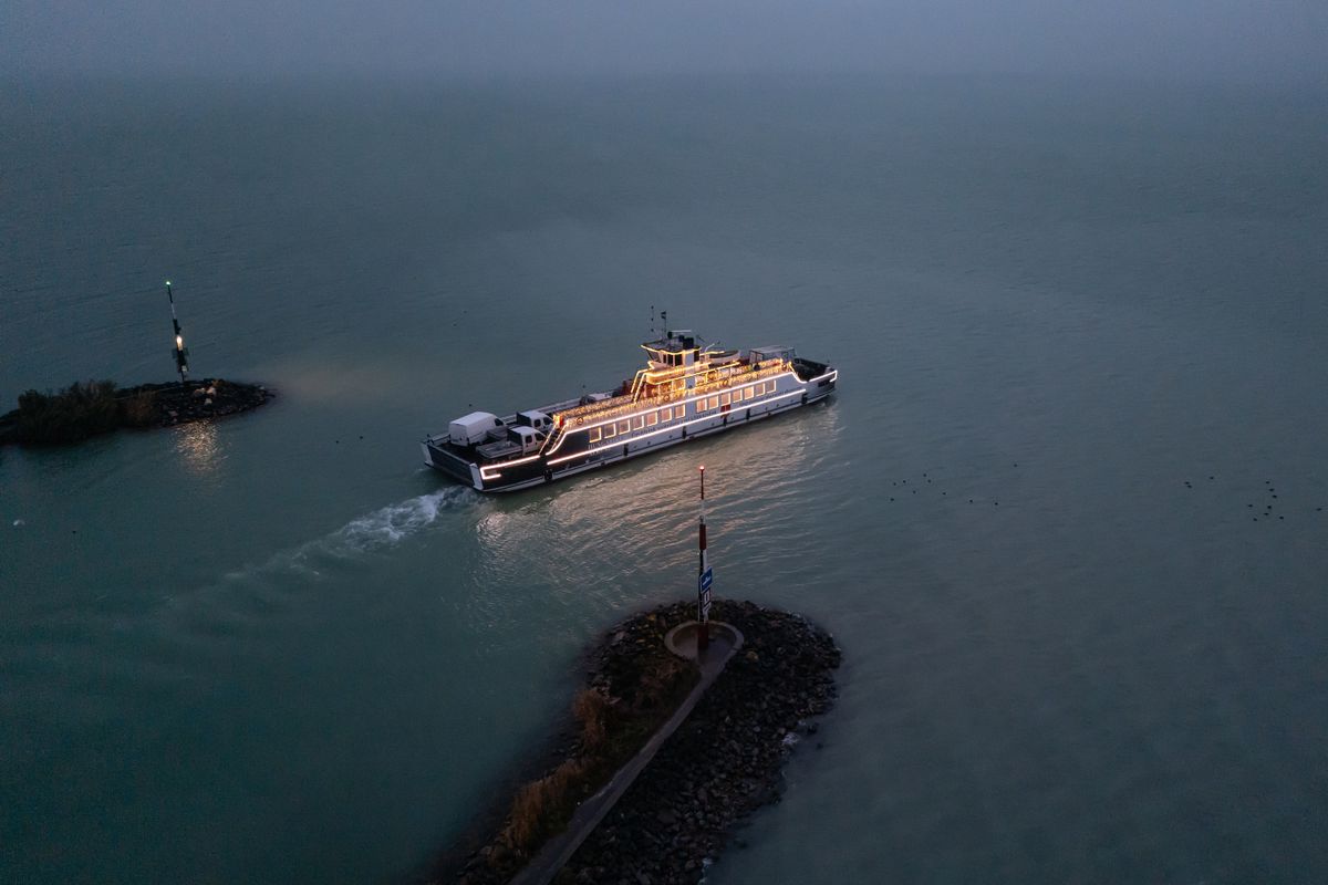 Szántód, 2025. december 3.
A drónnal készült felvételen ünnepi fényekkel díszített komp a Balatonon Szántódnál 2025. december 3-án. A „fénykomp” november utolsó hétvégéjétől 2026. január 31-ig közlekedik reggel 7:00-től 8:00-ig, az esti időszakban pedig 16:00 óra után.
MTI/Vasvári Tamás