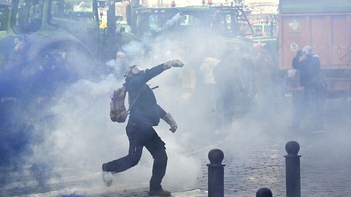 A farmer throws a stone as farmers clash with police officers near the European Parliament, during a farmers' protest to denounce the reforms of the Common Agricultural Policy (CAP) and trade agreements such as the Mercosur, in Brussels, on December 18, 2025, organised by Copa-Cogeca, the main association representing farmers and agricultural cooperatives in the EU. EU Farmers, particularly in France, worry the Mercosur deal -- which will be discussed at the EU leaders meeting -- will see them undercut by a flow of cheaper goods from agricultural giant Brazil and its neighbours. They also oppose plans put forward by the European Commission to overhaul the 27-nation bloc's huge farming subsidies, fearing less money will flow their way. (Photo by NICOLAS TUCAT / AFP)