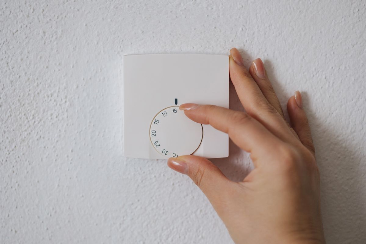 Human hand turns off the heating at home. Central Heating thermostat control dial adjustment