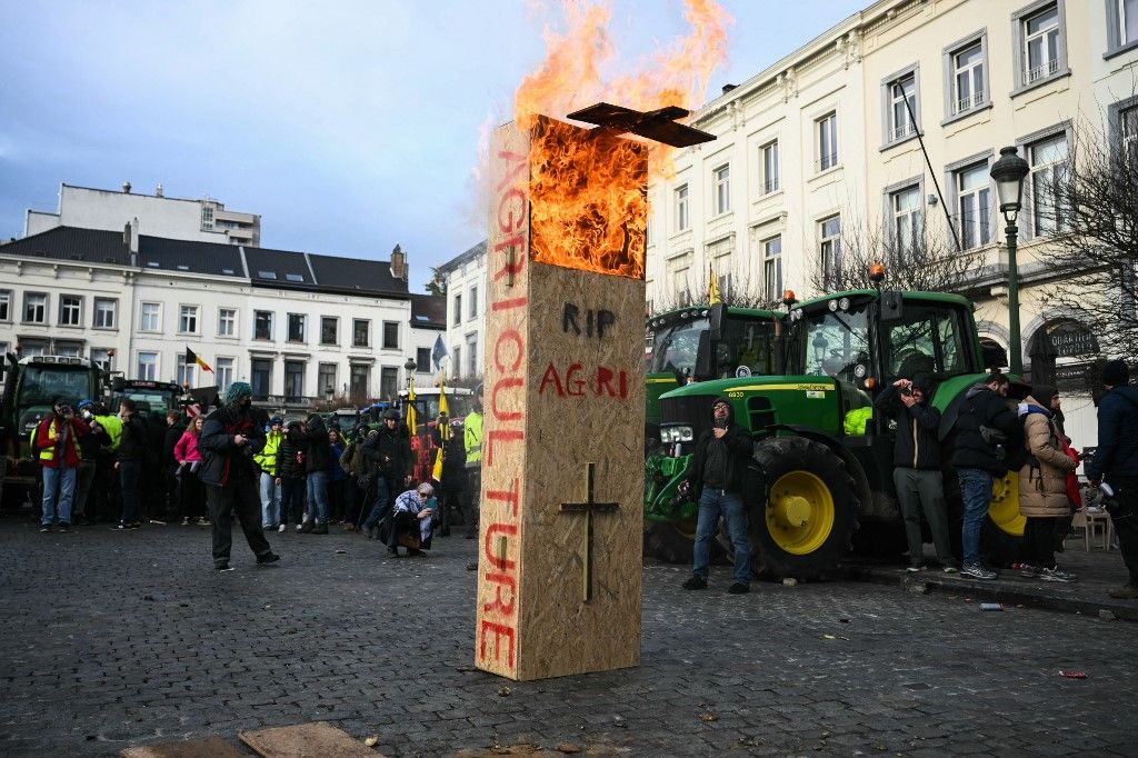 Farmers put on fire a fake coffin with the words "RIP farming" near the European Parliament, during a farmers' protest to denounce the reforms of the Common Agricultural Policy (CAP) and trade agreements such as the Mercosur, in Brussels, on December 18, 2025, organised by Copa-Cogeca, the main association representing farmers and agricultural cooperatives in the EU. EU Farmers, particularly in France, worry the Mercosur deal -- which will be discussed at the EU leaders meeting -- will see them undercut by a flow of cheaper goods from agricultural giant Brazil and its neighbours. They also oppose plans put forward by the European Commission to overhaul the 27-nation bloc's huge farming subsidies, fearing less money will flow their way. (Photo by NICOLAS TUCAT / AFP)