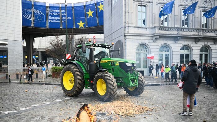 Farmers stand next to potatoes and a tractor parked in front of the European Parliament, during a farmers' protest to denounce the reforms of the Common Agricultural Policy (CAP) and trade agreements such as the Mercosur, in Brussels, on December 18, 2025, organised by Copa-Cogeca, the main association representing farmers and agricultural cooperatives in the EU. EU Farmers, particularly in France, worry the Mercosur deal -- which will be discussed at the EU leaders meeting -- will see them undercut by a flow of cheaper goods from agricultural giant Brazil and its neighbours. They also oppose plans put forward by the European Commission to overhaul the 27-nation bloc's huge farming subsidies, fearing less money will flow their way. (Photo by NICOLAS TUCAT / AFP)