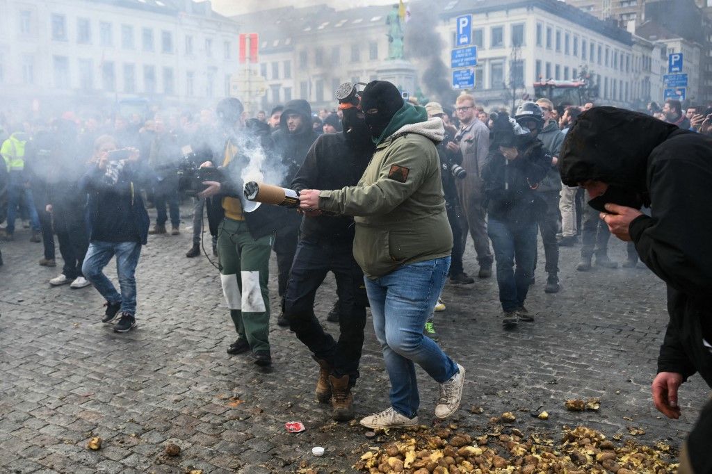 Farmers use a pyrotechnic device in front of the European Parliament, during a farmers' protest to denounce the reforms of the Common Agricultural Policy (CAP) and trade agreements such as the Mercosur, in Brussels, on December 18, 2025, organised by Copa-Cogeca, the main association representing farmers and agricultural cooperatives in the EU. EU Farmers, particularly in France, worry the Mercosur deal -- which will be discussed at the EU leaders meeting -- will see them undercut by a flow of cheaper goods from agricultural giant Brazil and its neighbours. They also oppose plans put forward by the European Commission to overhaul the 27-nation bloc's huge farming subsidies, fearing less money will flow their way. (Photo by NICOLAS TUCAT / AFP)