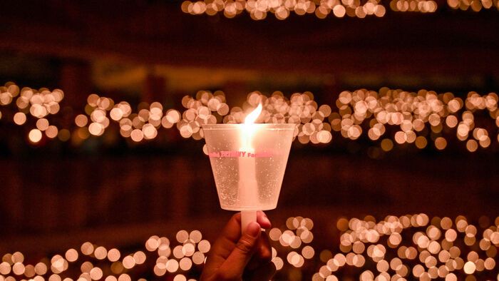 Egy keresztény hívő gyertyát tart a karácsonyi misén a surabayai Bethany templomban