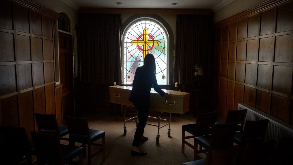 Amy Lilleywhite, partner of Lilleywhite Funeral Services, moves a body into a chapel of rest at their funeral home in Manchester, northern England on May 26, 2020. Lilleywhite Funeral Services, a family business established 1897, has experienced a significant increase in work largely due to the excess mortality associated with the Coronavirus pandemic. The Funeral Services' operations have been affected by Coronavirus, with staff wearing full PPE when dealing with the body of any person who'd previously tested positive for Covid-19. (Photo by OLI SCARFF / AFP)