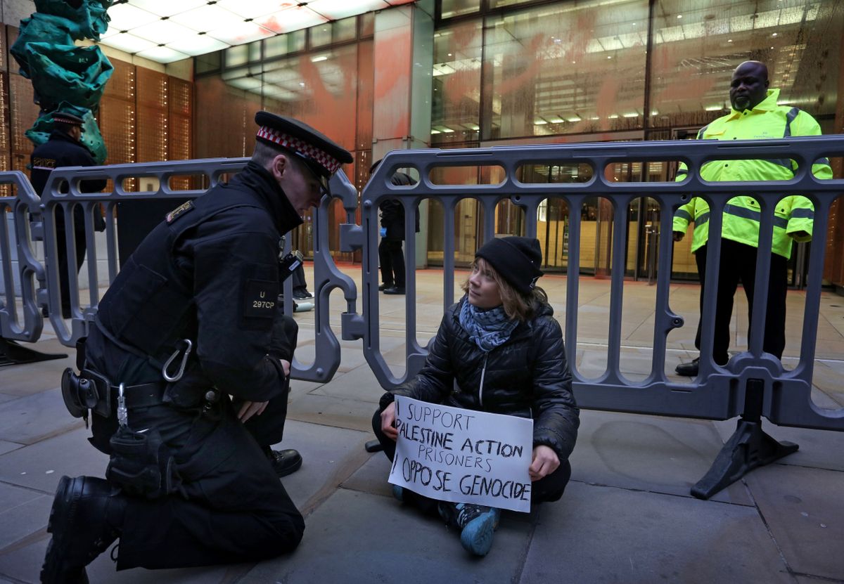 A handout photograph taken on and released by Prisoners for Palestine in London on December 23, 2025 shows Swedish activist Greta Thunberg before her arrest by Police officers outside the offices of Aspen Insurance at Plantation Place on Fenchurch Street. London police on Tuesday arrested Swedish activist Greta Thunberg at a demonstration in support of pro-Palestinian hunger strikers, Palestinian activist groups said. "Greta Thunberg was arrested under the Terrorism Act at the Prisoners for Palestine lock-on protest," Prisoners for Palestine said in a statement. (Photo by Prisoners for Palestine / AFP) / RESTRICTED TO EDITORIAL USE - MANDATORY CREDIT "AFP PHOTO / Prisoners for Palestine / HANDOUT " - NO MARKETING NO ADVERTISING CAMPAIGNS - DISTRIBUTED AS A SERVICE TO CLIENTS