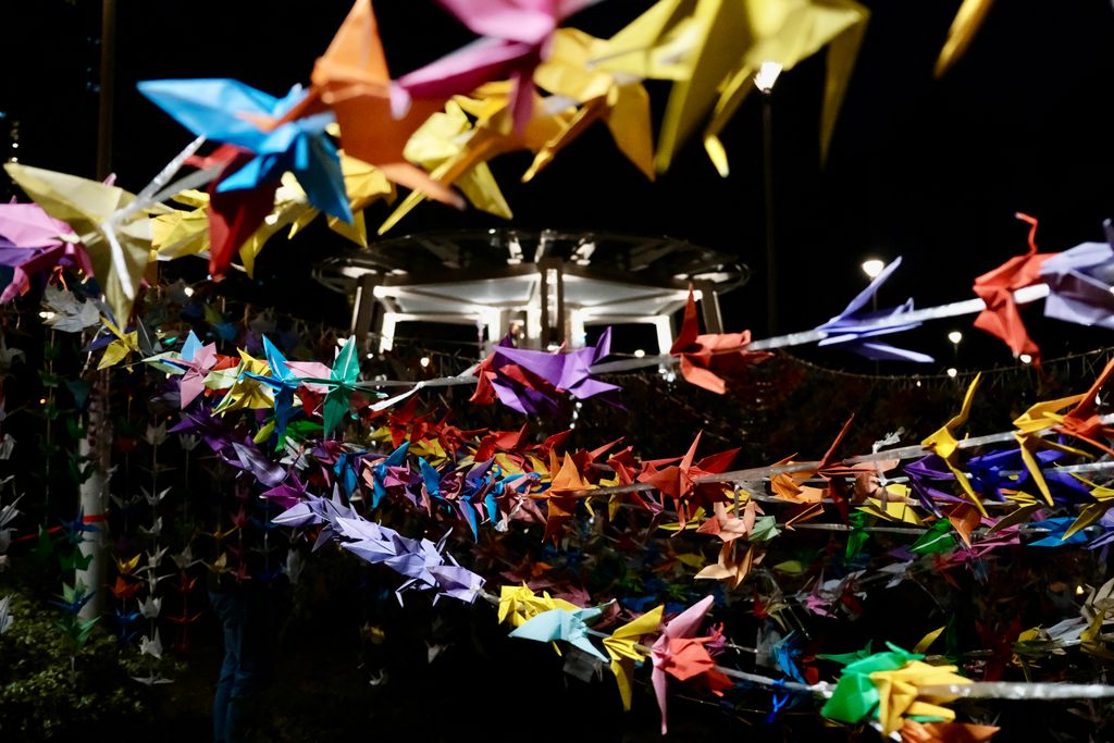 Színes papírdarvak lógnak lakóházak között a hongkongi tűzvész áldozatainak emlékére