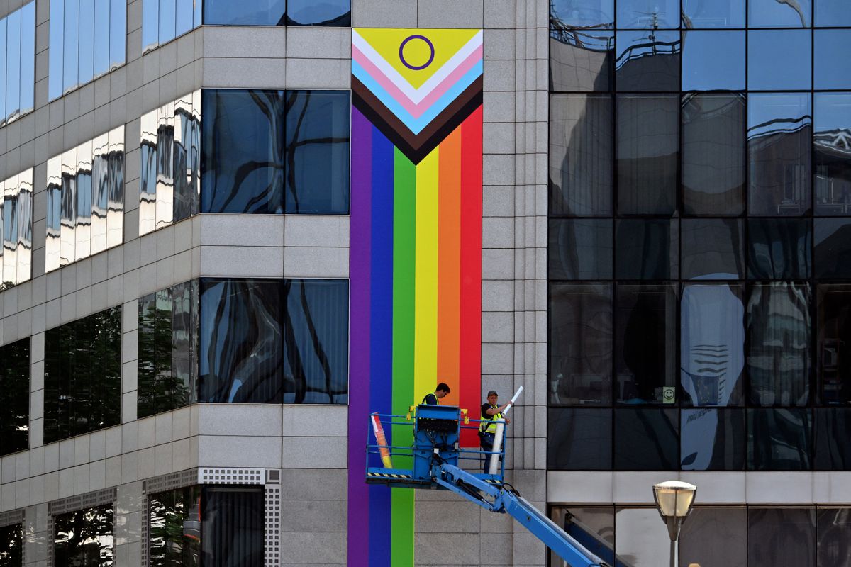 Workers put up giant LGBTQI flags on the facade of a building of the European Council on May 13, 2025 in Brussels, a few days ahead of the Brussels' Pride. (Photo by Nicolas TUCAT / AFP)