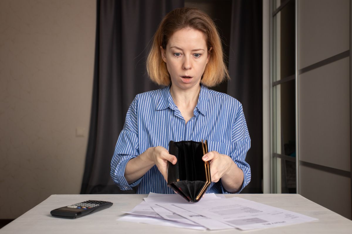 Woman with an empty wallet and utility bills, budget calculation and cost of living, household expenses and money crisis.