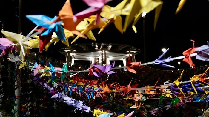 Színes papírdarvak lógnak lakóházak között a hongkongi tűzvész áldozatainak emlékére