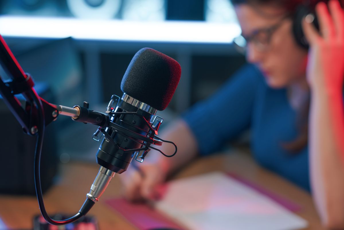 Presenter working at the radio broadcasting studio, professional microphone in the foreground
