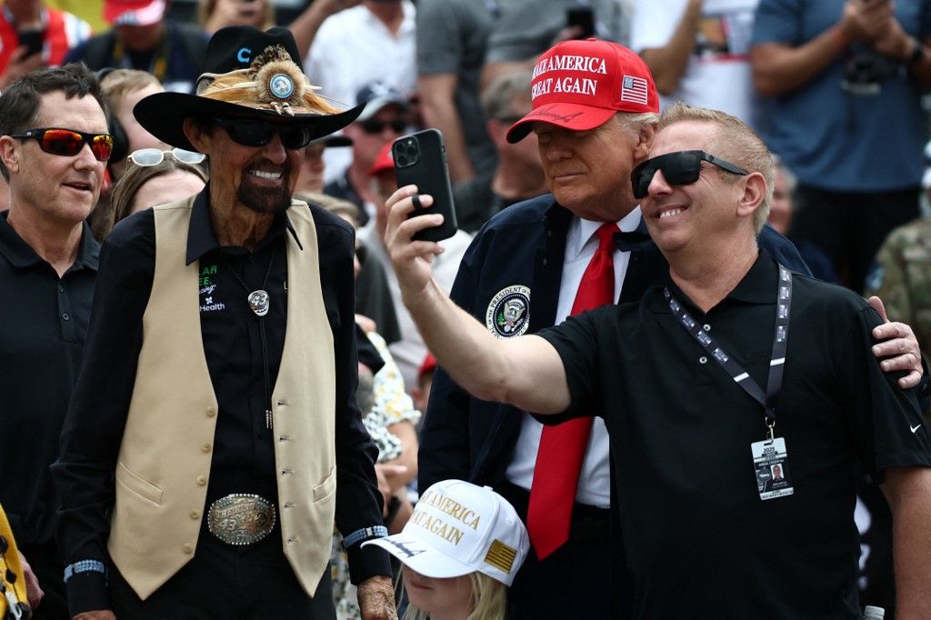 US PPresident Donald Trump takes a selfie with former NASCAR Cup series driver, Greg Biffle (R) and NASCAR Hall of Famer, Richard Petty prior to the NASCAR Cup Series Daytona 500 at Daytona International Speedway on February 16, 2025 in Daytona Beach, Florida. (Photo by Chris Graythen / POOL / AFP)