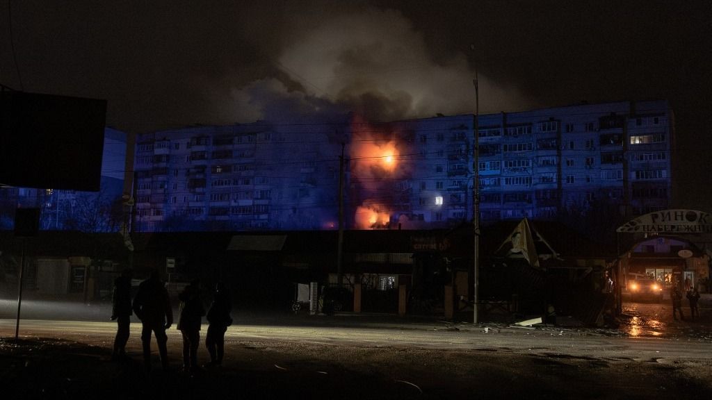 People look at a residential building on fire following a Russian drone attack on the city of Vyshhorod, in the Kyiv region early on November 30, 2025, amid the Russian invasion of Ukraine. (Photo by Roman PILIPEY / AFP)