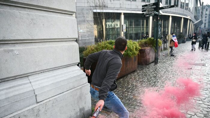 A farmer throws a smoke flare can as farmers clash with police officers near the European Parliament, during a farmers' protest to denounce the reforms of the Common Agricultural Policy (CAP) and trade agreements such as the Mercosur, in Brussels, on December 18, 2025, organised by Copa-Cogeca, the main association representing farmers and agricultural cooperatives in the EU. EU Farmers, particularly in France, worry the Mercosur deal -- which will be discussed at the EU leaders meeting -- will see them undercut by a flow of cheaper goods from agricultural giant Brazil and its neighbours. They also oppose plans put forward by the European Commission to overhaul the 27-nation bloc's huge farming subsidies, fearing less money will flow their way. (Photo by NICOLAS TUCAT / AFP)