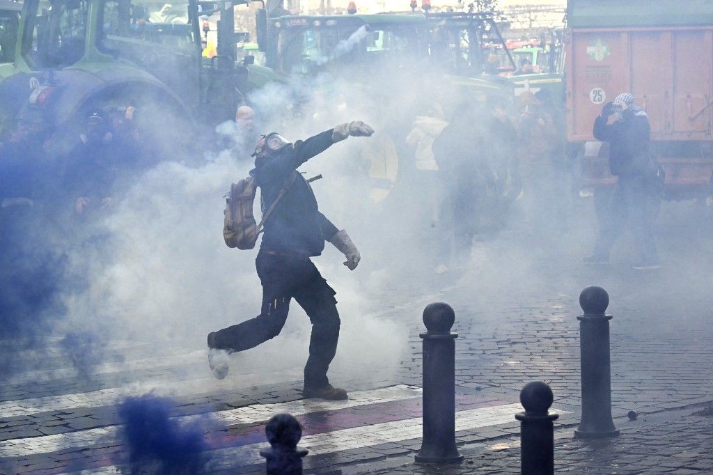 A farmer throws a stone as farmers clash with police officers near the European Parliament, during a farmers' protest to denounce the reforms of the Common Agricultural Policy (CAP) and trade agreements such as the Mercosur, in Brussels, on December 18, 2025, organised by Copa-Cogeca, the main association representing farmers and agricultural cooperatives in the EU. EU Farmers, particularly in France, worry the Mercosur deal -- which will be discussed at the EU leaders meeting -- will see them undercut by a flow of cheaper goods from agricultural giant Brazil and its neighbours. They also oppose plans put forward by the European Commission to overhaul the 27-nation bloc's huge farming subsidies, fearing less money will flow their way. (Photo by NICOLAS TUCAT / AFP)