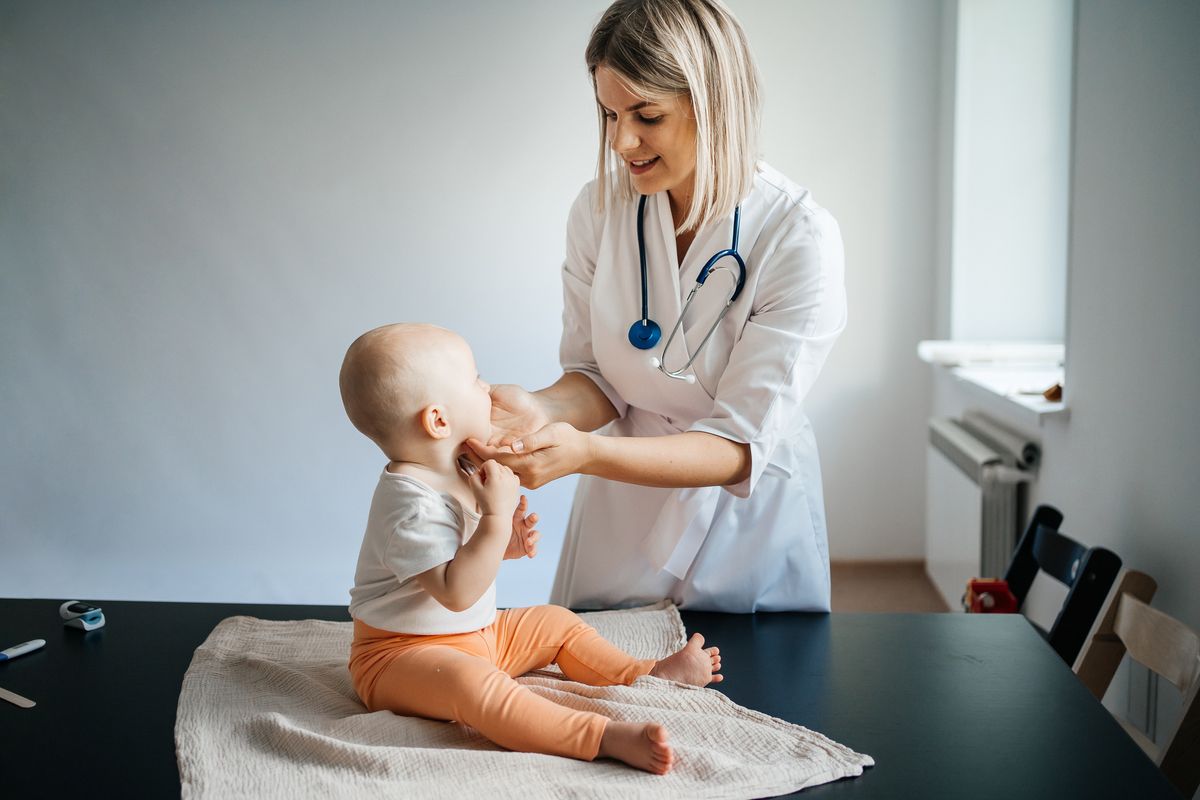 doctor pediatrician in a white coat carefully examines the baby