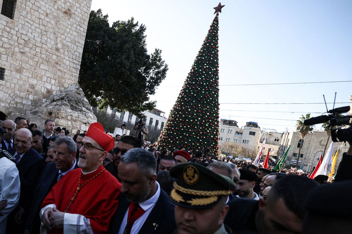 Latin Patriarch of Jerusalem Italian Pierbattista Pizzaballa is welcomed by pilgrims, tourists and Palestinians as he arrive to lead the Christmas Mass in the Church of the Nativity in the Israeli-occupied West Bank city of Bethlehem, believed to be the birthplace of Jesus Christ, on December 24, 2025. Palestinian Scouts marched under a clear blue sky in Bethlehem on December 24, 2025, as the Palestinian city emerged from the shadow of the war in Gaza to celebrate its first festive Christmas in more than two years. Throughout the Gaza war that began with Hamas's attack on Israel in October 2023, a sombre tone marked Chistmases in Bethlehem, the biblical birthplace of Jesus Christ. (Photo by HAZEM BADER / AFP)
