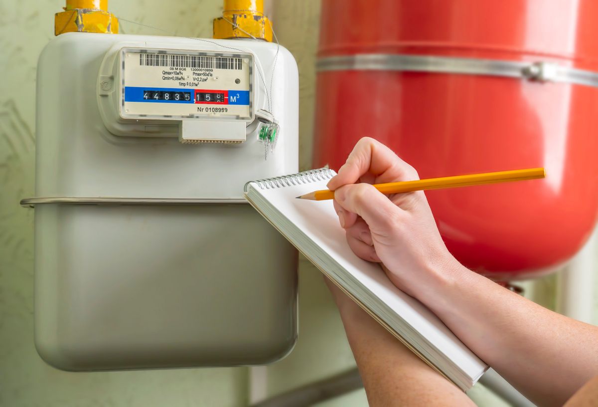 person writes indication gas meter in notebook.