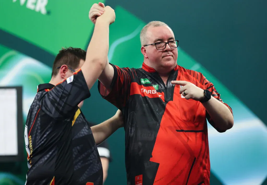 Stephen Bunting sportszerűen a lengyel Sebastian Bialeckit élteti a győzelme után a darts-világbajnokságon a tiebreakben kivított sikere után