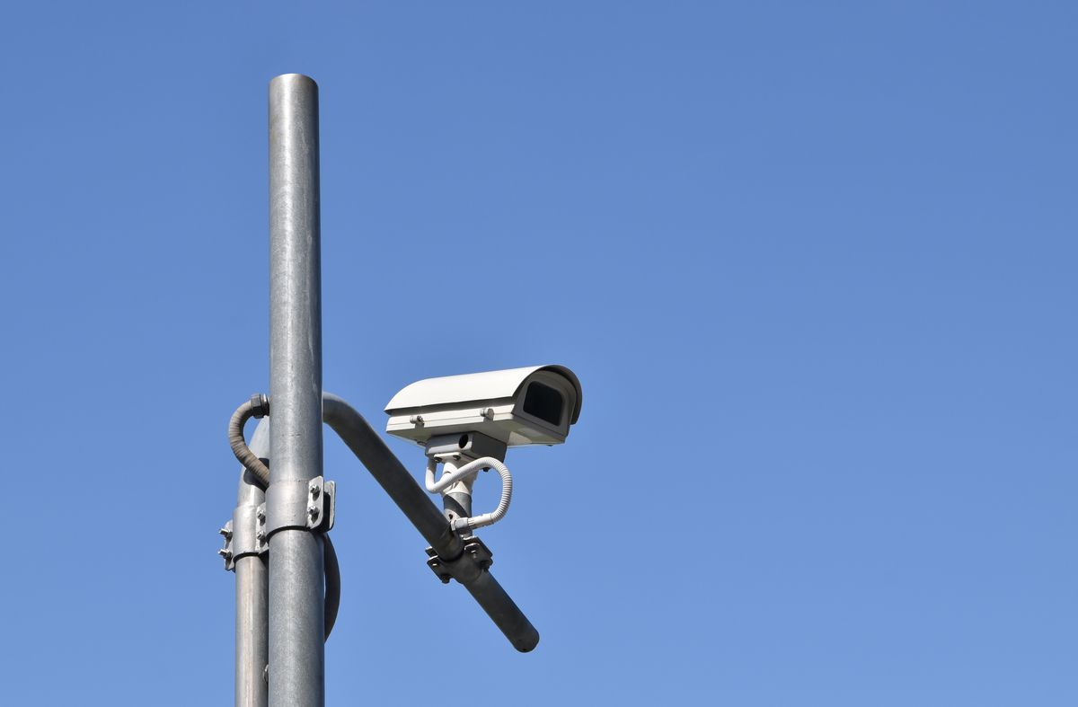security cctv camera on gray steel post and clear blue sky with copy space, urban surveillance street camera