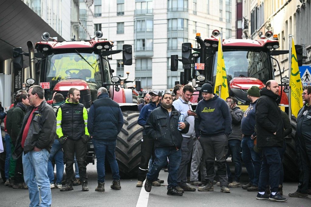 Farmers stand in front of tractors near the European Parliament, during a farmers' protest to denounce the reforms of the Common Agricultural Policy (CAP) and trade agreements such as the Mercosur, in Brussels, on December 18, 2025, organised by Copa-Cogeca, the main association representing farmers and agricultural cooperatives in the EU. EU Farmers, particularly in France, worry the Mercosur deal -- which will be discussed at the EU leaders meeting -- will see them undercut by a flow of cheaper goods from agricultural giant Brazil and its neighbours. They also oppose plans put forward by the European Commission to overhaul the 27-nation bloc's huge farming subsidies, fearing less money will flow their way. (Photo by NICOLAS TUCAT / AFP)