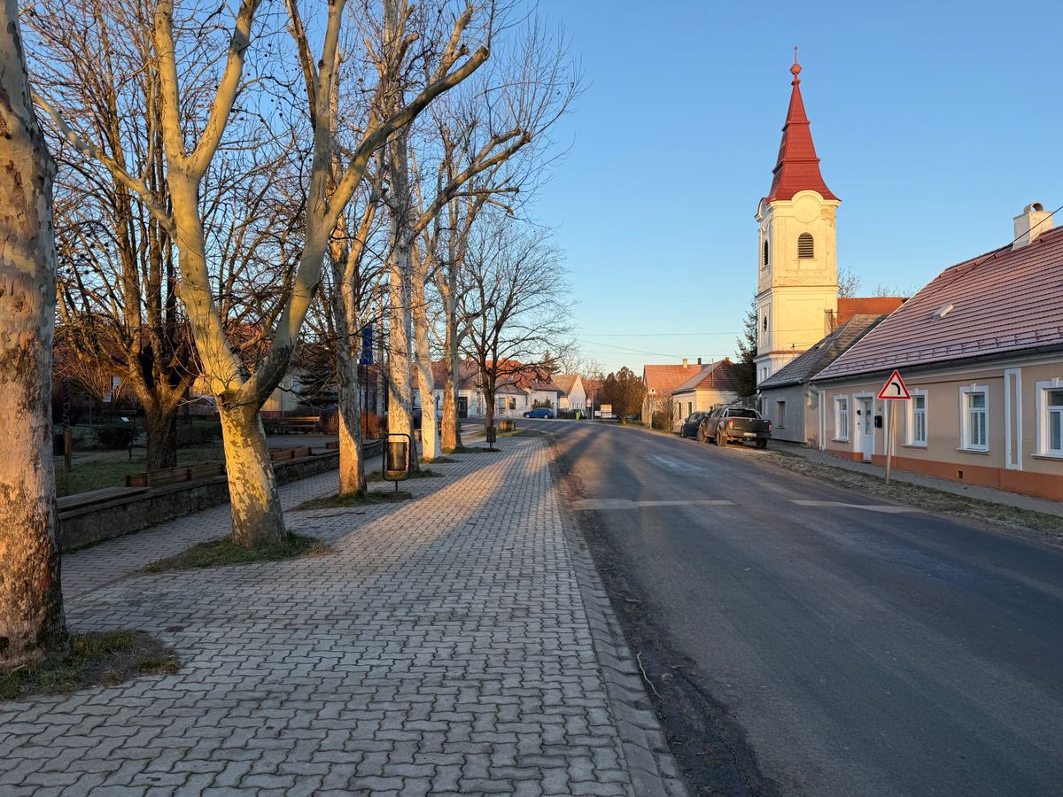 Nagyvazsony, Hungary – December 26, 2024: Street view of the village of Nagyvazsony in winter with church tower and residential buildings under clear sky.