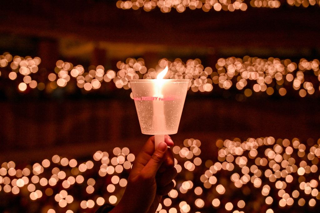 Egy keresztény hívő gyertyát tart a karácsonyi misén a surabayai Bethany templomban