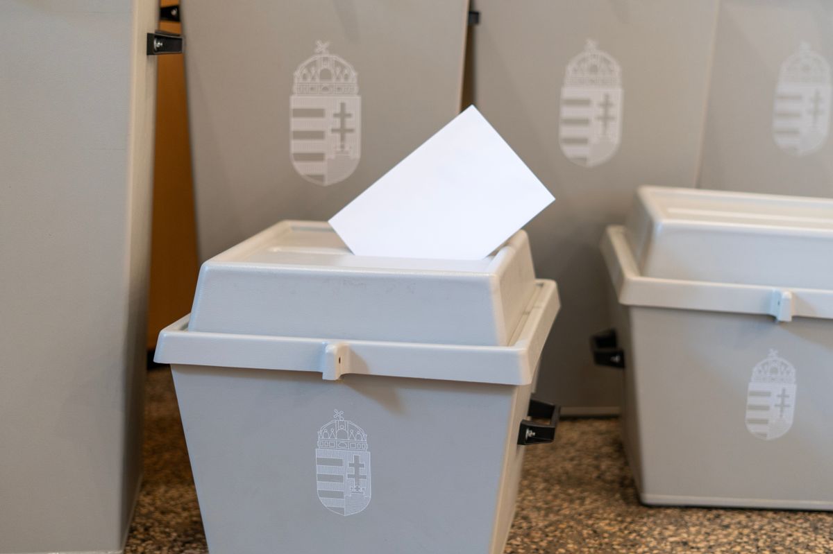 Ballot box with Hungarian state coat of arms and voting envelope on a table