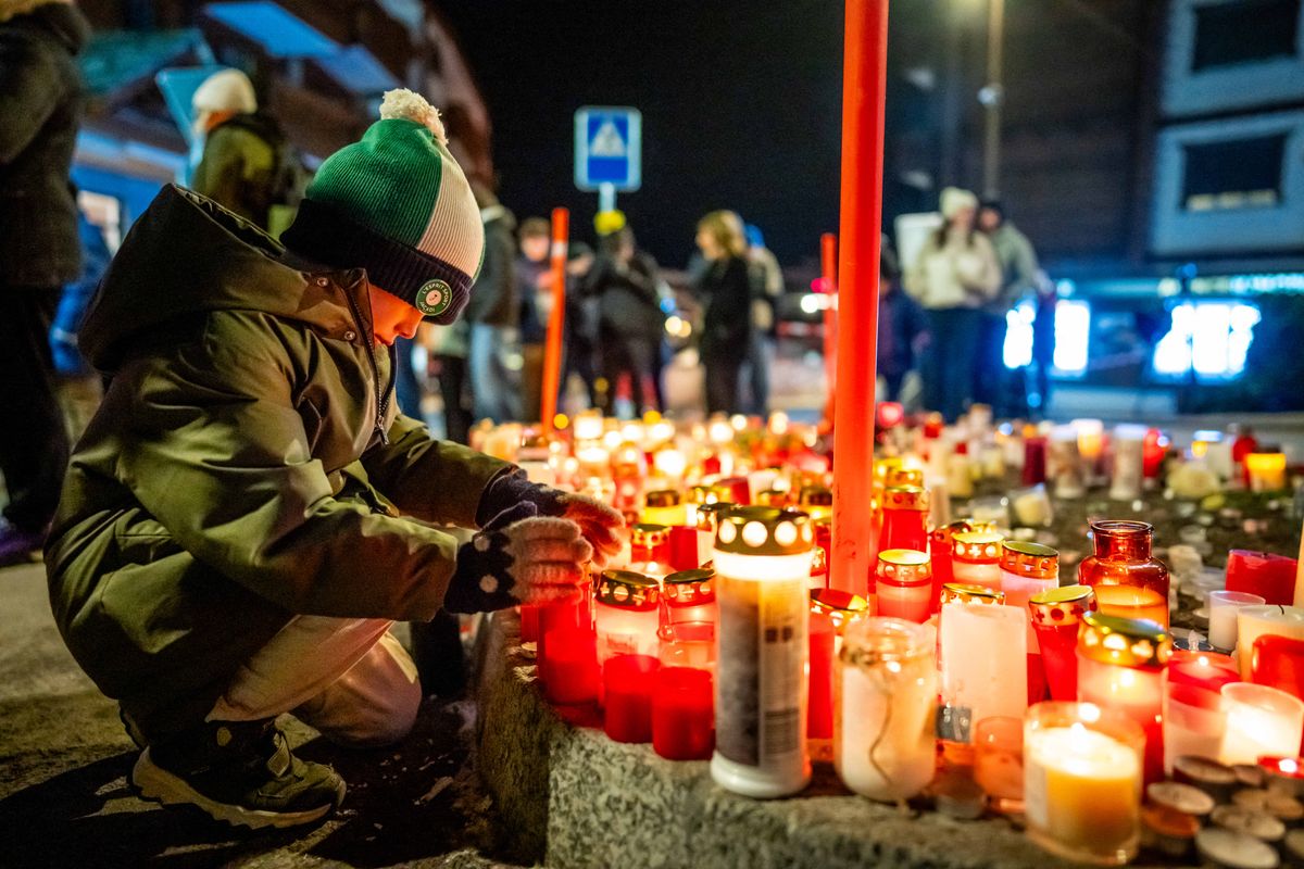 A mourner lights a candle at a makeshift memorial near the site of a fire that ripped through a bar during New Year's Eve celebrations in the Alpine ski resort town of Crans-Montana killing around 40 people and injuring more than 100 others, in Crans-Montana on January 2, 2026. Investigators raced on January 2, 2026 to identify the victims of a fire that ripped through a bar in the Swiss Alps town of Crans-Montana, turning a New Year's celebration into one of the country's worst tragedies. Frederic Gisler, police commander in the Wallis canton in southwestern Switzerland, told reporters that authorities had counted "around 40 people who have died and around 115 injured, most of them seriously". tűz (Photo by MAXIME SCHMID / AFP)