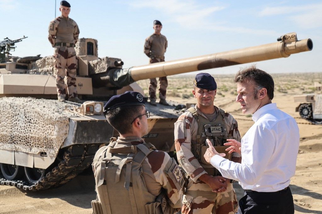 France's President Emmanuel Macron meets with French soldiers in front of a Leclerc tank during a troop?maneuver exercise near the 5th Cuirassier Regiment's base outside Zayed Military City on December 22, 2025. Macron arrived in the United Arab Emirates on December 21 to celebrate Christmas with French troops and to discuss bilateral ties with the Gulf state, as France hopes for more cooperation in its fight against drug trafficking. (Photo by Ludovic MARIN / AFP)