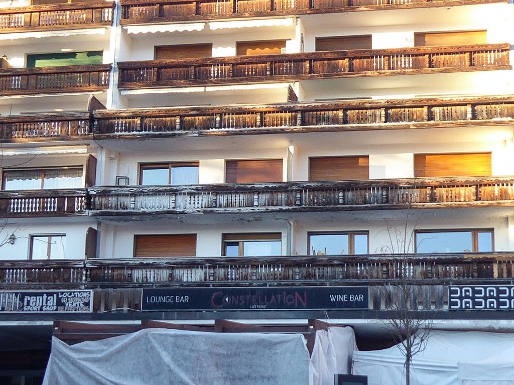 A photo shows a buildings' balconies over a blocked-off zone outside the "Le Constellation" bar following a fire at the establishment during New Year's Eve celebrations, killing 40 people and injuring 119, in the Alpine ski resort town of Crans-Montana, on January 3, 2026. Swiss investigators worked on January 3 to identify the victims and exact cause of the blaze that killed 40 New Year revellers at a packed bar in the ski resort of Crans-Montana. Dozens of people badly burnt in the fire early on January 1 in the glitzy Alpine town were taken to nearby countries for urgent treatment, while authorities pointed the finger at lit sparklers attached to champagne bottles igniting foam on the ceiling. Most of the 119 people wounded in the fire remained in critical condition. (Photo by Robin MILLARD / AFP)