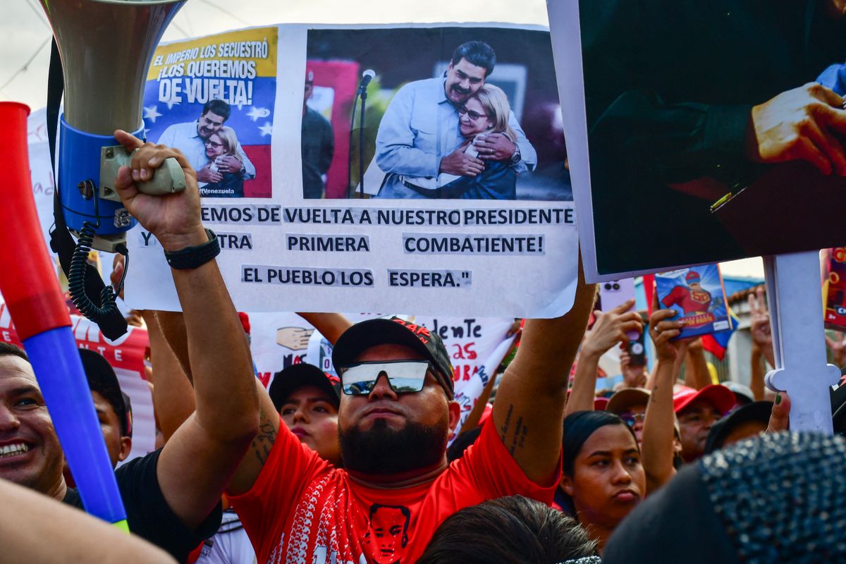 A demonstrator holds a picture of ousted Venezuela's President Nicolás Maduro and his wife Cilia Florez during a rally in their support in Valencia, Carabobo state, Venezuela on January 10, 2026. The US State Department on January 10, urged Americans in Venezuela to leave the country "immediately," citing risks from armed militias searching vehicles for US citizens at roadblocks. (Photo by Jacinto OLIVEROS / AFP)
