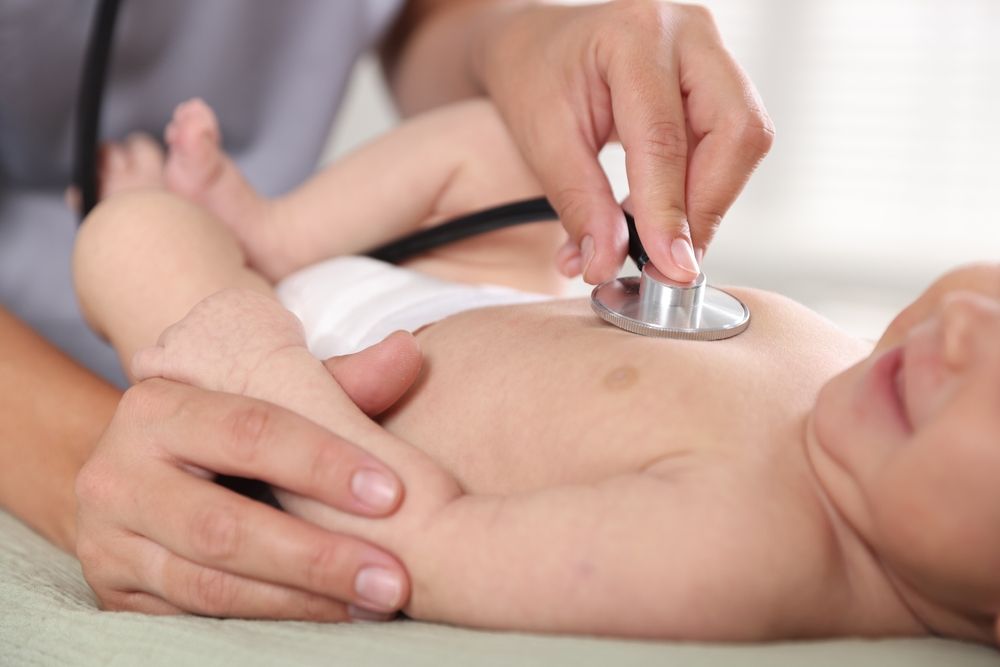 Doctor examining cute little child with stethoscope in hospital, closeup. Checking baby's health