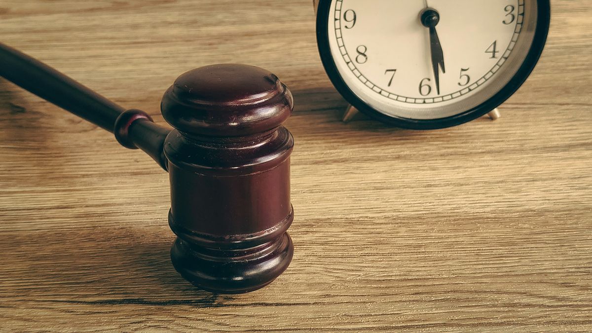 Gavel and alarm clock on a wooden table, symbolizing a legal deadline or time-sensitive court matter.