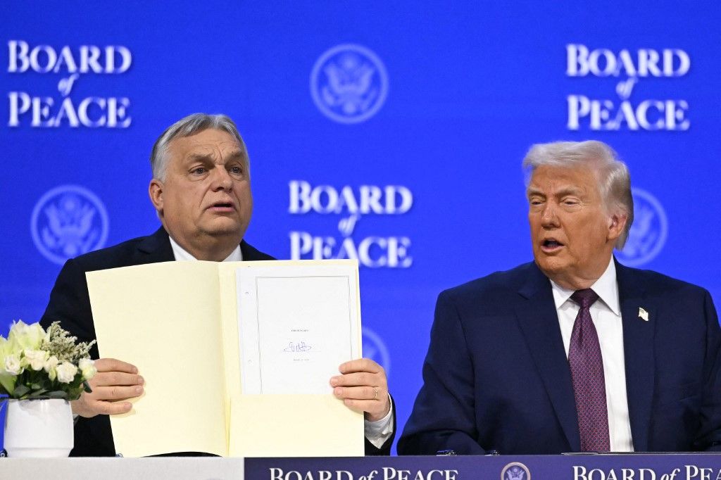 Hungary's Prime Minister Viktor Orban (L) holds a founding charter next to US President Donald Trump at the "Board of Peace" meeting during the World Economic Forum (WEF) annual meeting in Davos on January 22, 2026. US President Donald Trump will show off his new "Board of Peace" at Davos on January 22, 2026 burnishing his claim to be a peacemaker a day after backing off his own threats against Greenland. Originally meant to oversee the rebuilding of Gaza after the war between Hamas and Israel, the board's charter does not limit its role to the Strip, and has sparked concerns that Trump wants it to rival the United Nations. (Photo by Fabrice COFFRINI / AFP)