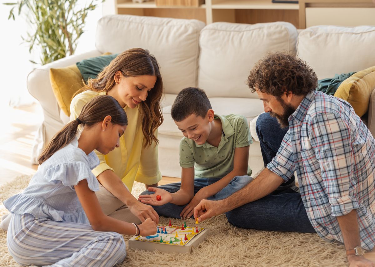 Family gathered in cozy living room plays board game together, filled with laughter and smiles