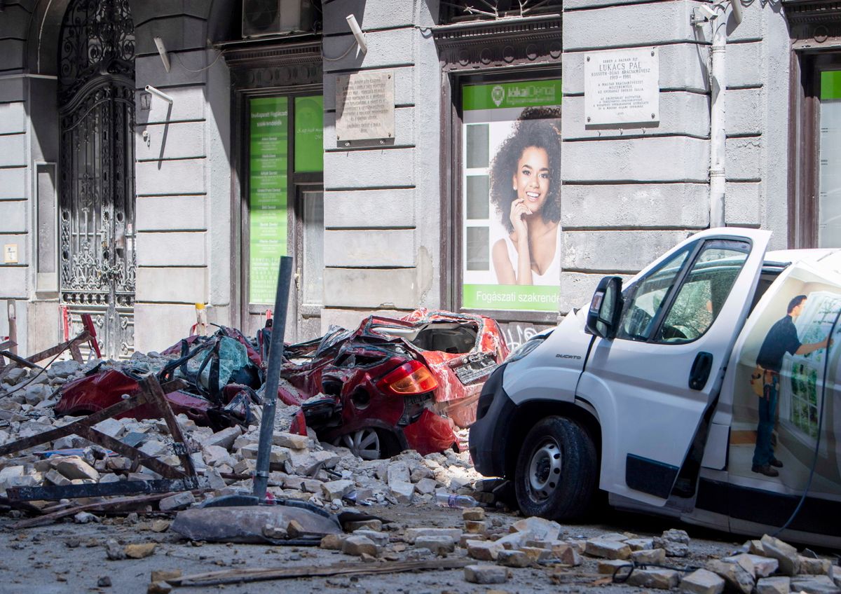 Budapest, 2022. június 28.
Összeroncsolódott autók a VI. kerület Aradi és a Jókai utca kereszteződésében található ötszintes épület előtt 2022. június 28-án, amelynek homlokzati fal és tetőszerkezeti elemei az előző nap az utcára és parkoló autókra dőltek.
MTI/Balogh Zoltán