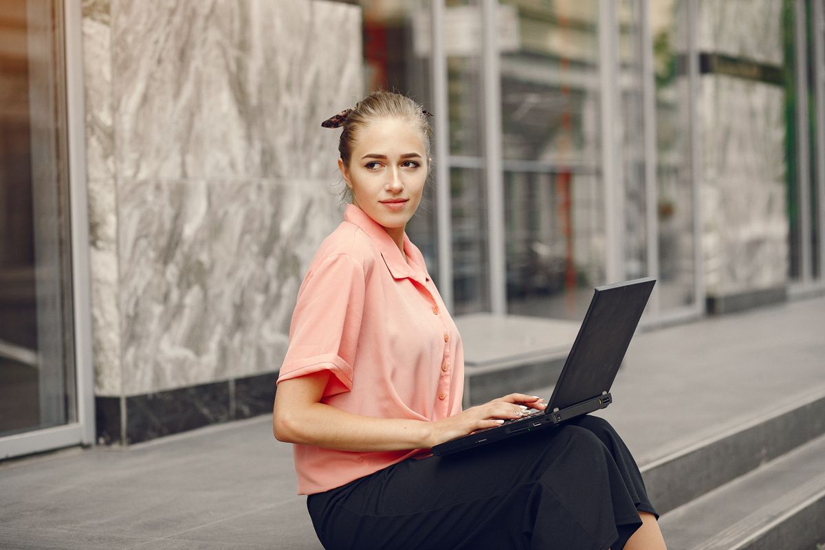 Girl with laptop. Student study in a city. Lady in a pink shirt.