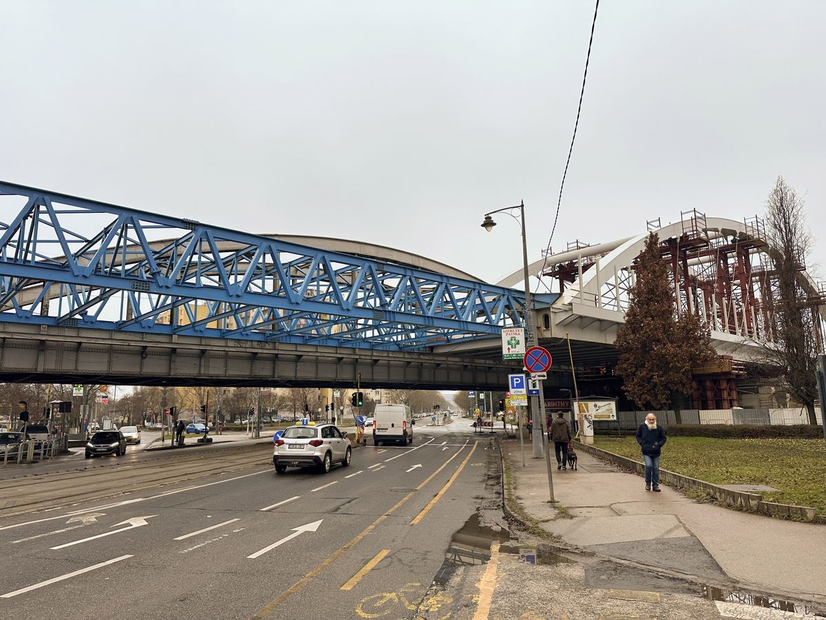 Budapest, 2026. február 2.
Az újonnan összeszerelt kétszer kétvágányos acélhíd első szerkezeti eleme és az áttoláshoz használt segédszerelvénye a helyére illesztése előtt a Bartók Béla úti közúti-vasúti átjárónál 2026. február 2-án. A fejlesztés része a Kelenföld és Ferencváros közötti vasútvonal kapacitásbővítésének, amely a Déli Körvasút kialakításának második üteméhez kapcsolódik.
MTI/Hatházi Tamás