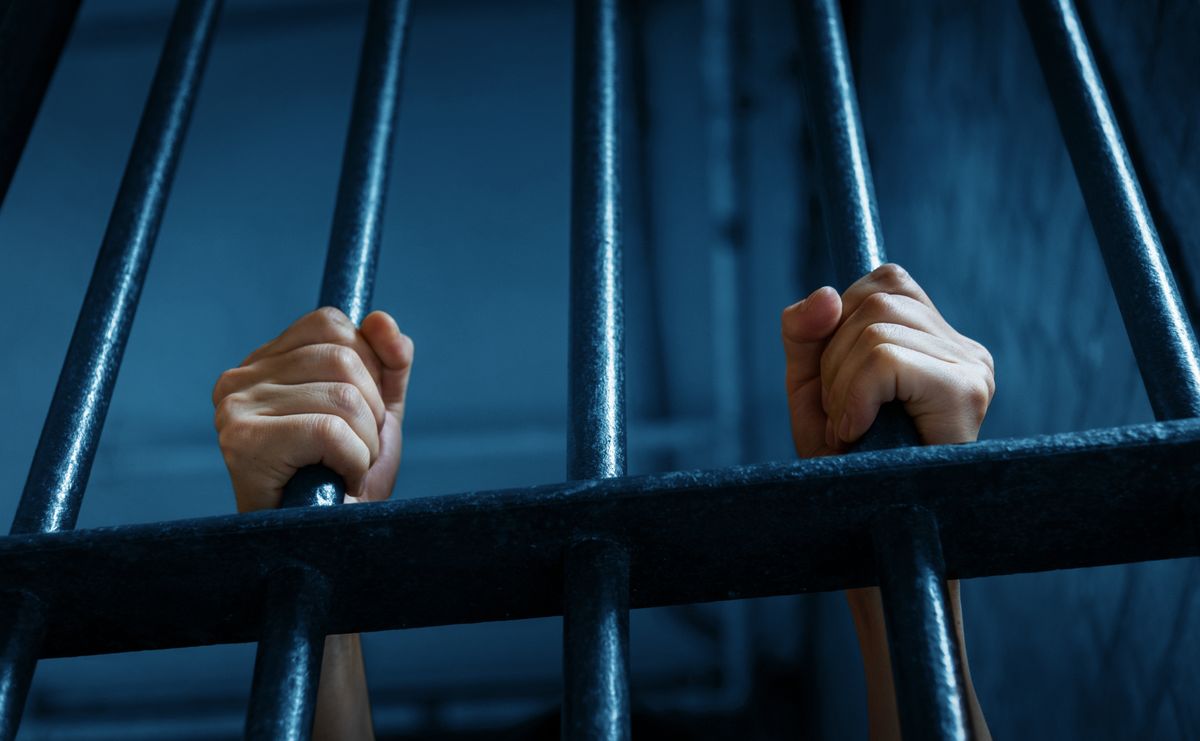 Women's hands holding prison railings