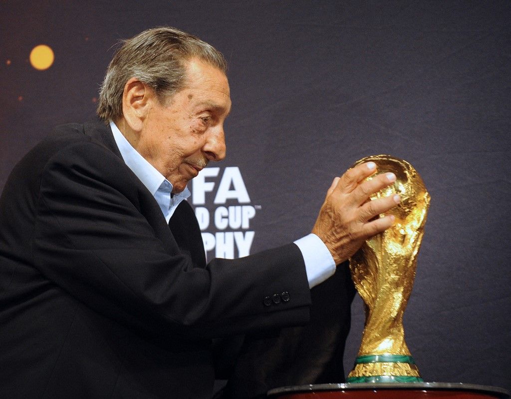Former footballer Alcides Ghiggia, 86, the last survivor of Uruguay's shock win over Brazil in the deciding match of the 1950 World Cup at the Maracana Stadium, touches the FIFA World Cup trophy during its exhibition in Montevideo as part of a world tour ahead of the Brazil 2014 World Cup tournament, on January 16, 2014.   AFP PHOTO/ Miguel ROJO (Photo by MIGUEL ROJO / AFP)