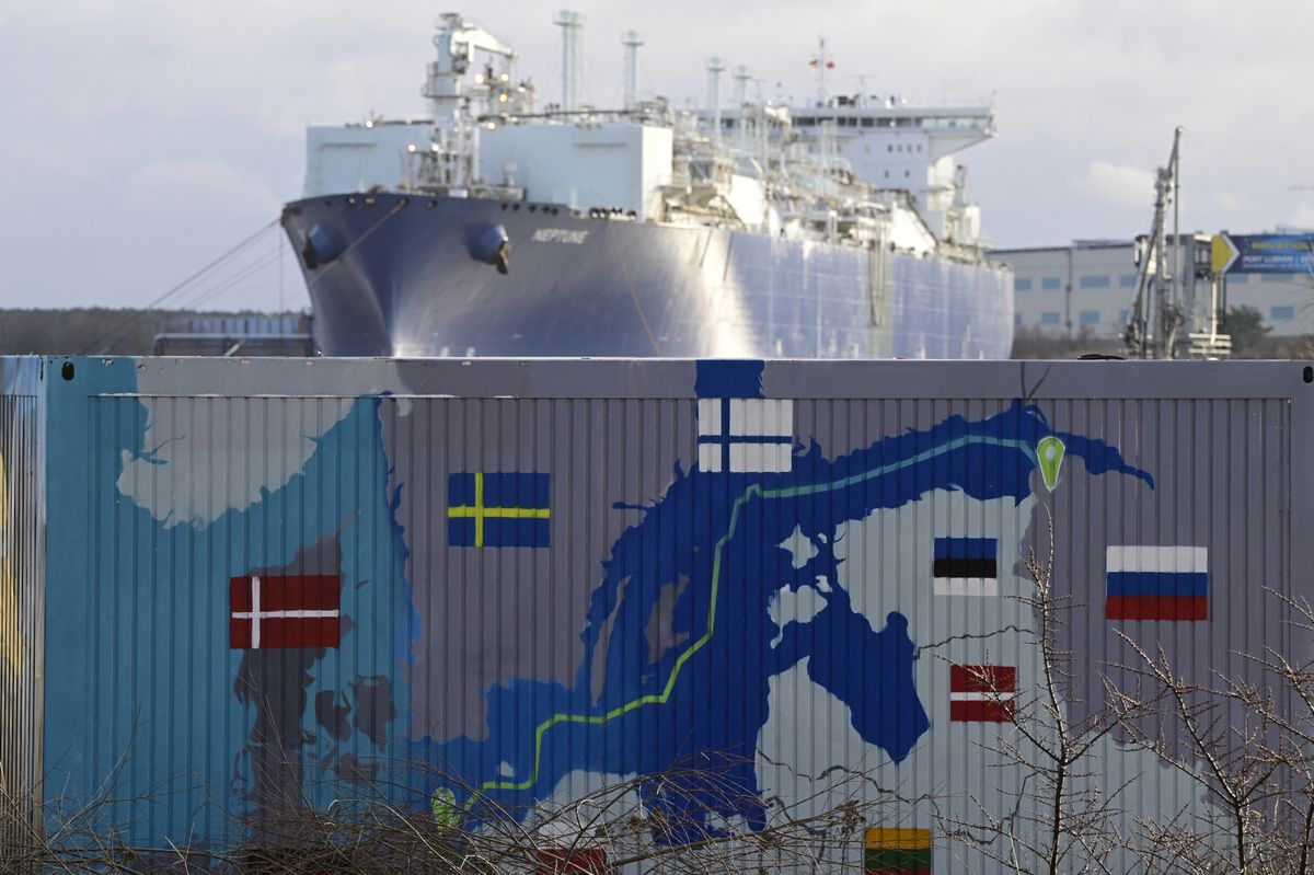 Floating Storage and Regasification Unit (FSRU) "Neptune" is pictured behind a container painted with a map showing the Nord Stream 2 gas pipeline, which was expected to deliver Russian gas to European households, in Lubmin's industrial park, northeastern Germany,at the harbour in Lubmin, ahead the official commissioning of the liquefied natural gas (LNG) terminal 'Deutsche Ostsee' in Lubmin, on January 14, 2023. (Photo by John MACDOUGALL / AFP)