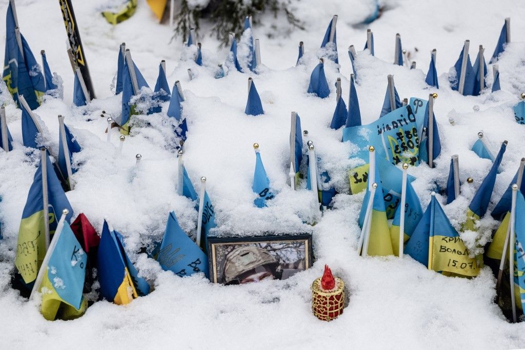 A photograph of a soldier at the Maidan memorial is covered with snow alongside numerous Ukrainian flags bearing the names of fallen soldiers in Kyiv, Ukraine on 30 January 2026. The memorial remains in place as part of daily life in the city during winter conditions. (Photo by Daniel Yovkov / Hans Lucas via AFP)