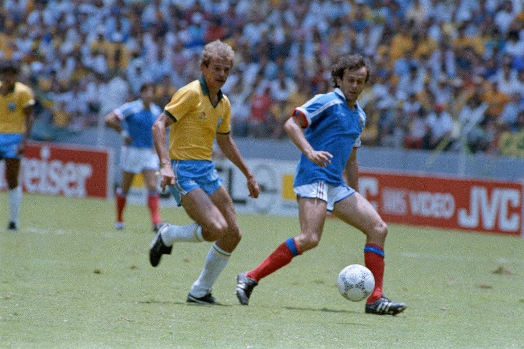French mildfielder Michel Platini ties the score at 1 as he kicks the ball past his Brazilian counterpart Alemao during the FIFA football World Cup quarter finals between France and Brazil on June 21, 1986 in Guadalajara. France beat Brazil 4-3 on penalty kicks. The 1986 FIFA World Cup was the thirteenth edition of the tournament, which is held every four years. Held in Mexico from 31 May to 29 June, it was won by Argentina, led by the 25-year-old Diego Maradona, who was at the peak of his career. (Photo by Georges GOBET / AFP)